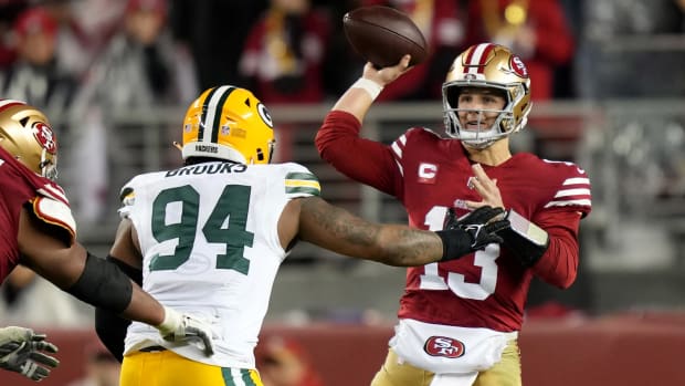 Brock Purdy throws the ball as a Packers player rushes at him